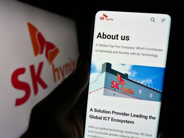 Stuttgart, Almanya - 11-16-2023: Güney Kore yarı iletken şirketi SK hynix Inc. 'in internet sayfası ile logo önünde cep telefonu tutan kişi. Telefon ekranının merkezine odaklan.