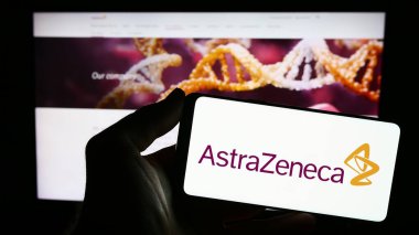 Stuttgart, Almanya - 11-16-2023: İnternet sitesi önünde üzerinde ilaç şirketi AstraZeneca plc 'nin logosu bulunan akıllı telefon sahibi kişi. Telefon ekranına odaklan.
