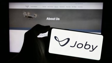 Stuttgart, Almanya - 11-16-2023: İş sayfası önünde ABD 'li eVTOL uçak şirketi Joby Aviation' ın logosuyla cep telefonu tutan kişi. Telefon ekranına odaklan.