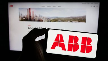 Stuttgart, Almanya - 11-16-2023: İnternet sitesinin önünde üzerinde ABB Ltd. logosu olan akıllı telefon sahibi kişi. Telefon ekranına odaklan.