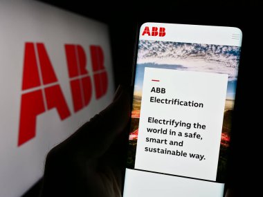 Stuttgart, Almanya - 11-16-2023: İş logosu önünde ABB Ltd. 'nin web sitesi olan akıllı telefon sahibi kişi. Telefon ekranının merkezine odaklan.