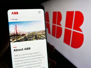 Stuttgart, Almanya - 11-16-2023: İş logosu önünde ABB Ltd. 'nin web sayfası ile cep telefonu tutan kişi. Telefon ekranının merkezine odaklan.