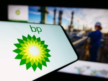 Stuttgart, Almanya - 11-16-2023: İngiliz petrol ve doğalgaz şirketi BP plc 'nin logosu olan cep telefonu iş sitesinin önünde. Telefon ekranının merkez soluna odaklan.