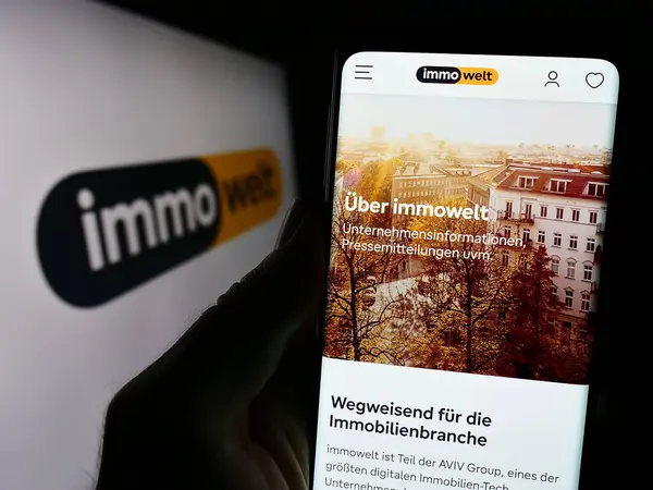 Stuttgart, Almanya - 11-16-2023: Alman emlak platformu şirketi Immowelt GmbH 'in internet sayfası ile logo önünde cep telefonu tutan kişi. Telefon ekranının merkezine odaklan.