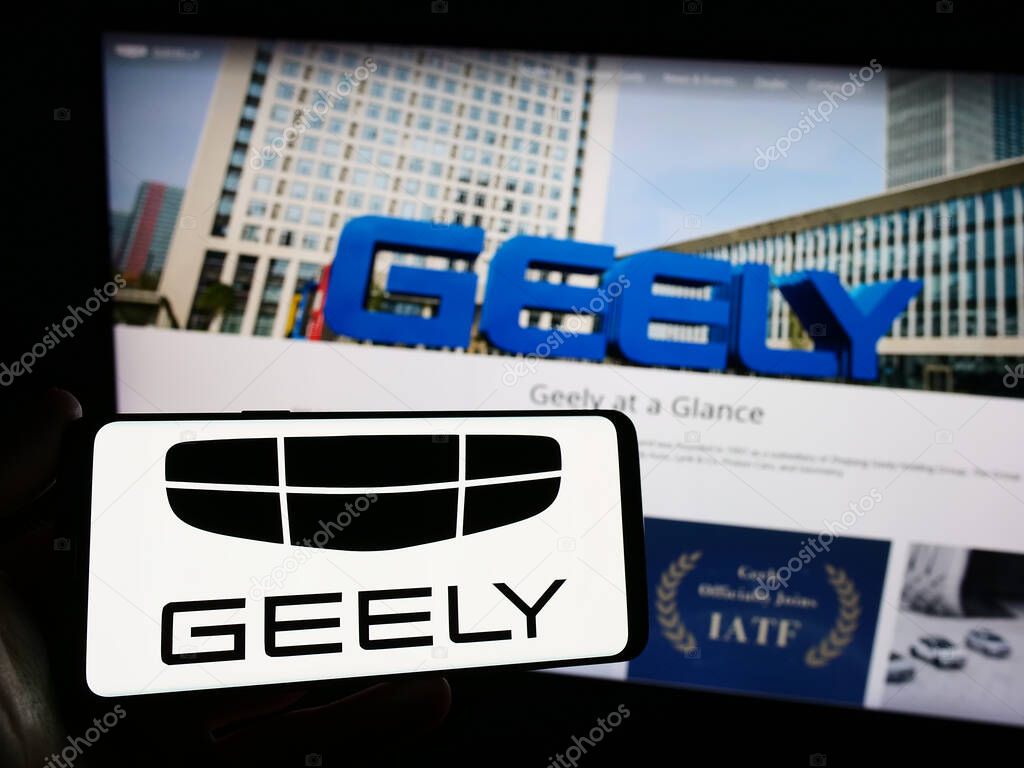 Stuttgart, Germany - 11-16-2023: Person holding smartphone with logo of Chinese car manufacturer Zhejiang Geely Holding Group in front of website. Focus on phone display.