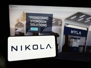 Stuttgart, Almanya - 11-17-2023: ABD 'li elektrikli araç şirketi Nikola Corporation' ın logosuyla cep telefonu sahibi kişi iş sayfası önünde. Telefon ekranına odaklan.