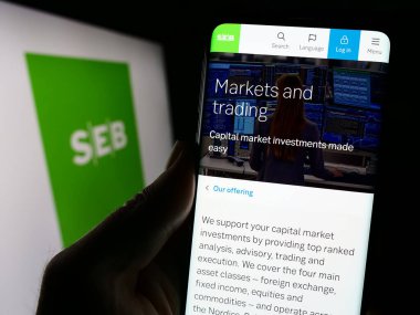 Stuttgart, Almanya - 11-17-2023: İsveçli şirket Skandinaviska Enskilda Banken AB 'nin (SEB) internet sayfası ile cep telefonu tutan kişi. Telefon ekranının merkezine odaklan.