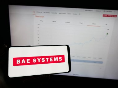 Stuttgart, Almanya - 11-21-2023: İngiliz havacılık ve savunma şirketi BAE Systems plc 'in logosuna sahip cep telefonu sahibi kişi web sayfasının önünde. Telefon ekranına odaklan.