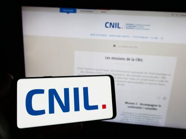 Stuttgart, Almanya - 11-21-2023: İnternet sitesi önünde üzerinde Nationale de l 'Informatique et des Libertes (CNIL) logosu bulunan kişi. Telefon ekranına odaklan.