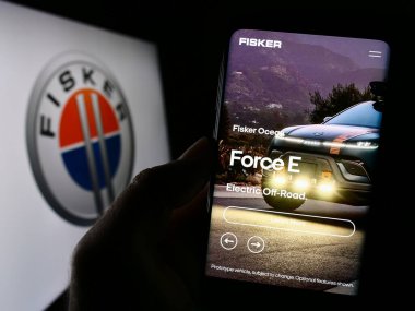 Stuttgart, Almanya - 11-21-2023: ABD 'li elektrikli araç şirketi Fisker Inc.' in logosuyla cep telefonu sahibi kişi iş sayfasının önünde. Telefon ekranına odaklan.