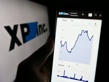 Stuttgart, Almanya - 11-22-2023: Brezilyalı yatırım şirketi XP Inc. 'nin web sitesi ile logo önünde akıllı telefon tutan kişi. Telefon ekranının merkezine odaklan.