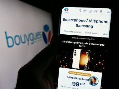 Stuttgart, Almanya - 11-22-2023: Fransız telekomünikasyon şirketi Bouygues Telecom S.A. 'nın logolu web sayfası ile cep telefonu tutan kişi. Telefon ekranının merkezine odaklan.