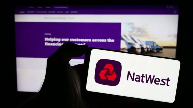 Stuttgart, Almanya - 11-22-2023: Finans şirketi National Westminster Bank 'ın (NatWest) logosuyla cep telefonu tutan kişi iş sayfası önünde. Telefon ekranına odaklan.