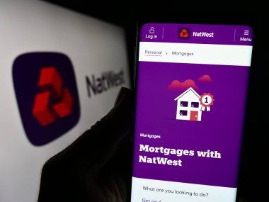 Stuttgart, Germany - 11-22-2023: Person holding smartphone with webpage of financial company National Westminster Bank (NatWest) with logo. Focus on center of phone display. clipart