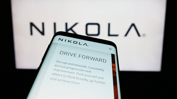 Stuttgart, Germany - 11-17-2023: Smartphone with website of US electric vehicle company Nikola Corporation in front of business logo. Focus on top-left of phone display.
