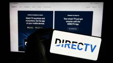 Stuttgart, Almanya - 11-22-2023: ABD 'li televizyon dağıtım şirketi DirecTV LLC' nin logosuyla cep telefonu sahibi kişi iş sayfası önünde. Telefon ekranına odaklan.
