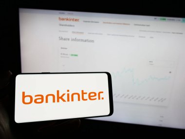 Stuttgart, Almanya - 11-22-2023: İspanyol finans hizmetleri şirketi Bankinter SA 'nın logosuna sahip cep telefonu sahibi kişi iş sayfasının önünde. Telefon ekranına odaklan.