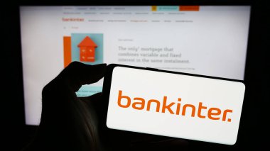 Stuttgart, Almanya - 11-22-2023: İspanyol finans hizmetleri şirketi Bankinter S.A. 'nın logosuyla cep telefonu tutan kişi iş sayfası önünde. Telefon ekranına odaklan.