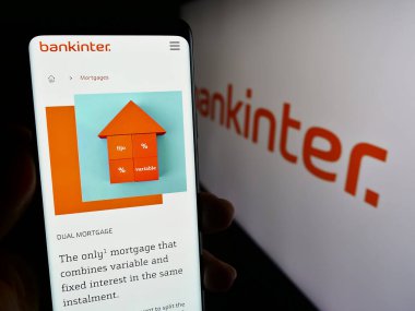 Stuttgart, Almanya - 11-22-2023: İspanyol finans hizmetleri şirketi Bankinter S.A. 'nın internet sayfası ile logo önünde cep telefonu tutan kişi. Telefon ekranının merkezine odaklan.