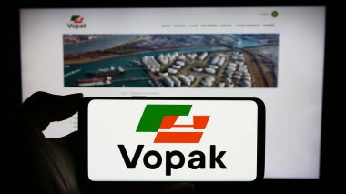 Stuttgart, Almanya - 11-23-2023: Hollandalı depolama şirketi Koninklijke Vopak N.V. 'nin logosuyla cep telefonu tutan kişi iş sayfasının önünde. Telefon ekranına odaklan.