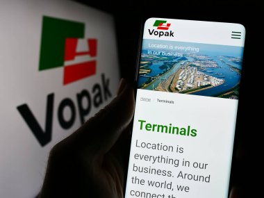 Stuttgart, Almanya - 11-23-2023: Hollandalı depolama şirketi Koninklijke Vopak NV 'nin web sayfası ile logo önünde cep telefonu tutan kişi. Telefon ekranının merkezine odaklan.