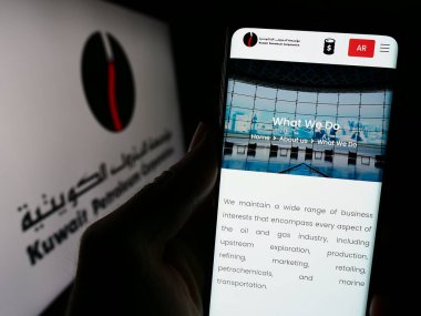Stuttgart, Almanya - 11-23-2023: Kuveyt petrol şirketi Kuveyt Petrol Şirketi 'nin (KPC) logolu web sayfası ile akıllı telefon tutan kişi. Telefon ekranının merkezine odaklan.