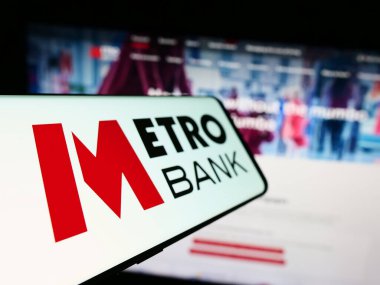 Stuttgart, Germany - 11-24-2023: Cellphone with logo of British financial services company Metro Bank plc in front of business website. Focus on left of phone display. clipart