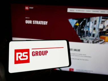 Stuttgart, Almanya - 11-24-2023: İngiliz elektrik dağıtım şirketi RS Group plc 'nin logosuna sahip cep telefonu sahibi kişi web sayfasının önünde. Telefon ekranına odaklan.