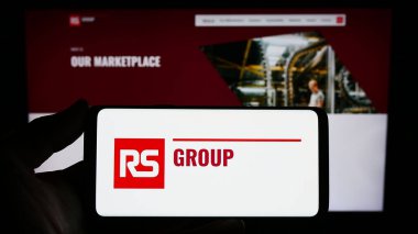 Stuttgart, Almanya - 11-24-2023: İngiliz elektrik dağıtım şirketi RS Group plc 'nin logosuna sahip akıllı telefon sahibi kişi web sitesi önünde. Telefon ekranına odaklan.