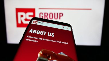 Stuttgart, Almanya - 11-24-2023: İngiliz elektrik dağıtım şirketi RS Group plc 'nin web sayfası ile birlikte cep telefonu iş logosu önünde. Telefon ekranının sol üst kısmına odaklan.