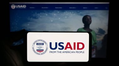 Stuttgart, Almanya - 11-27-2023: İnternet sitesi önünde ABD Uluslararası Kalkınma Dairesi (USAID) mührü taşıyan kişi. Telefon ekranına odaklan.