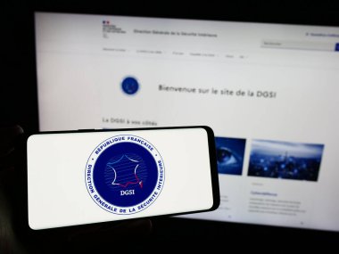 Stuttgart, Almanya - 11-27-2023: İnternet sitesinin önünde Yön Generali de la Securite Interieure (DGSI) logosuna sahip akıllı telefon sahibi kişi. Telefon ekranına odaklan.