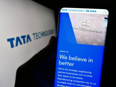 Stuttgart, Almanya - 11-28-2023: Hint mühendislik şirketi Tata Technologies Limited 'in web sitesi ile logo önünde cep telefonu tutan kişi. Telefon ekranının merkezine odaklan.