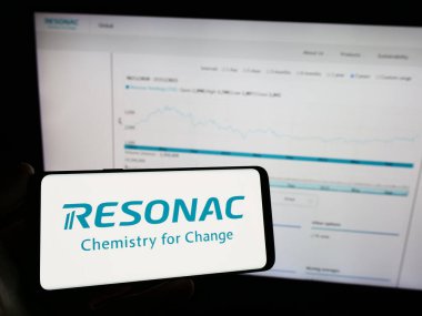 Stuttgart, Germany - 11-28-2023: Person holding mobile phone with logo of Japanese chemicals company Resonac in front of business web page. Focus on phone display. clipart