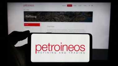 Stuttgart, Almanya - 11-28-2023: İngiliz petrol ve gaz şirketi PetroIneos Trading Limited 'in logosuna sahip cep telefonu sahibi kişi web sayfasının önünde. Telefon ekranına odaklan.