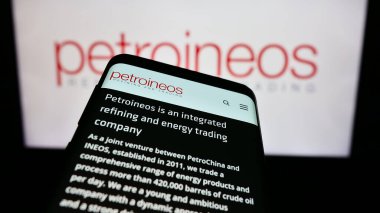 Stuttgart, Germany - 11-28-2023: Smartphone with website of British oil and gas company PetroIneos Trading Limited in front of business logo. Focus on top-left of phone display. clipart