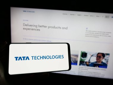 Stuttgart, Almanya - 11-28-2023: Üzerinde Hint mühendislik şirketi Tata Technologies Limited 'in logosu bulunan cep telefonu sahibi kişi iş sayfasının önünde. Telefon ekranına odaklan.