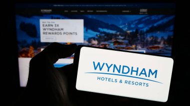 Stuttgart, Almanya - 11-29-2023: ABD 'li otel şirketi Wyndham Hotels and Resorts Inc.' in logosunun bulunduğu akıllı telefon sahibi kişi web sitesinin önünde. Telefon ekranına odaklan.