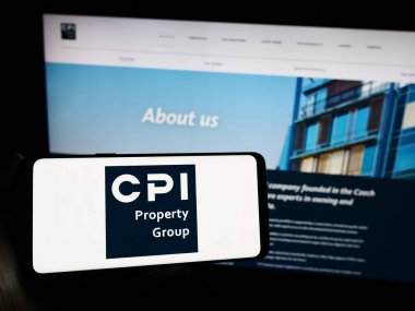 Stuttgart, Almanya - 11-29-2023: Web sitesi önünde üzerinde emlak şirketi CPI Property Group 'un (CPIPG) logosu bulunan akıllı telefon sahibi kişi. Telefon ekranına odaklan.
