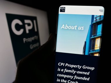 Stuttgart, Almanya - 11-29-2023: Emlak şirketi CPI Property Group 'un (CPIPG) logo önünde web sayfası bulunan kişi. Telefon ekranının merkezine odaklan.
