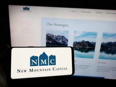 Stuttgart, Almanya - 11-29-2023: İnternet sitesi önünde ABD 'li yatırım şirketi New Mountain Capital' in (NMC) logosuna sahip kişi. Telefon ekranına odaklan.