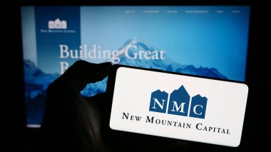 Stuttgart, Almanya - 11-29-2023: ABD 'li yatırım şirketi New Mountain Capital' in (NMC) logosuyla cep telefonu sahibi kişi iş sayfasının önünde. Telefon ekranına odaklan.