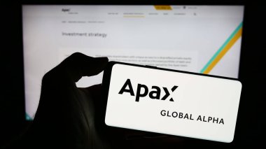 Stuttgart, Almanya - 11-30-2023: İngiliz yatırım şirketi Apax Global Alpha Limited 'in logosuna sahip cep telefonu sahibi kişi iş sayfasının önünde. Telefon ekranına odaklan.