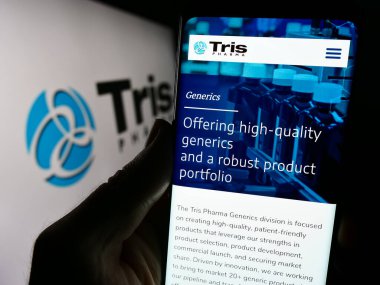 Stuttgart, Almanya - 11-30-2023: ABD 'li biyofarmasötik şirketi Tris Pharma Inc.' in web sayfası ile logo önünde cep telefonu tutan kişi. Telefon ekranının merkezine odaklan.