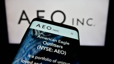 Stuttgart, Germany - 11-30-2023: Smartphone with website of US retail company American Eagle Outfitters Inc. (AEO) in front of business logo. Focus on top-left of phone display. clipart