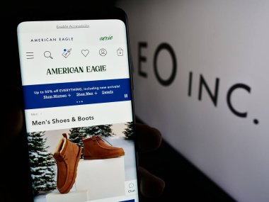 Stuttgart, Almanya - 11-30-2023: ABD 'li perakende şirketi American Eagle Outfitters Inc. (AEO)' nun internet sayfası ile cep telefonu tutan kişi. Telefon ekranının merkezine odaklan.