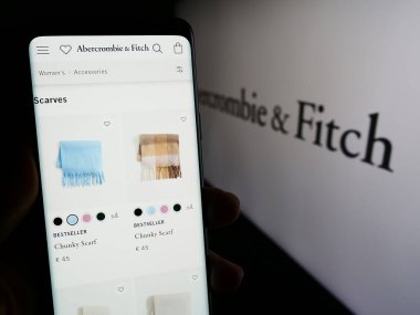 Stuttgart, Almanya - 11-30-2023: ABD 'li giyim perakende şirketi Abercrombie and Fitch Co.' nun web sayfası ile logo önünde cep telefonu tutan kişi. Telefon ekranının merkezine odaklan.
