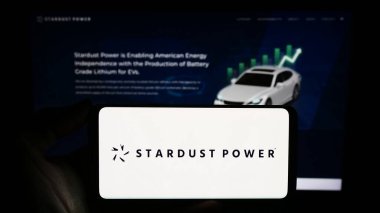 Stuttgart, Almanya - 11-30-2023: Sitenin önünde ABD 'li lityum arıtma şirketi Stardust Power Inc.' in logosuna sahip akıllı telefon sahibi kişi. Telefon ekranına odaklan.