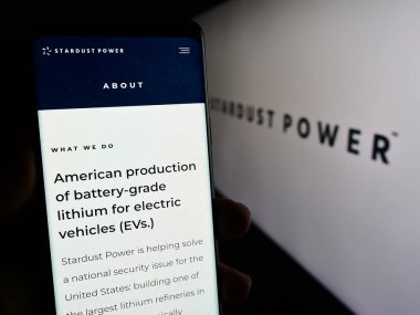 Stuttgart, Almanya - 11-30-2023: ABD 'li lityum arıtma şirketi Stardust Power Inc.' in web sayfası ile logo önünde cep telefonu tutan kişi. Telefon ekranının merkezine odaklan.