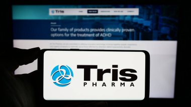 Stuttgart, Almanya - 11-30-2023: İş sayfası önünde ABD 'li biyofarmasötik şirketi Tris Pharma Inc.' in logosuyla cep telefonu bulunduran kişi. Telefon ekranına odaklan.